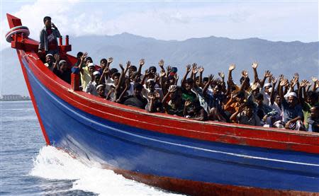 Ethnic Rohingya refugees from Myanmar wave as they are transported by a wooden boat to a temporary shelter in Krueng Raya in Aceh Besar, in this file picture taken April 8, 2013. REUTERS/Junaidi Hanafiah/Files