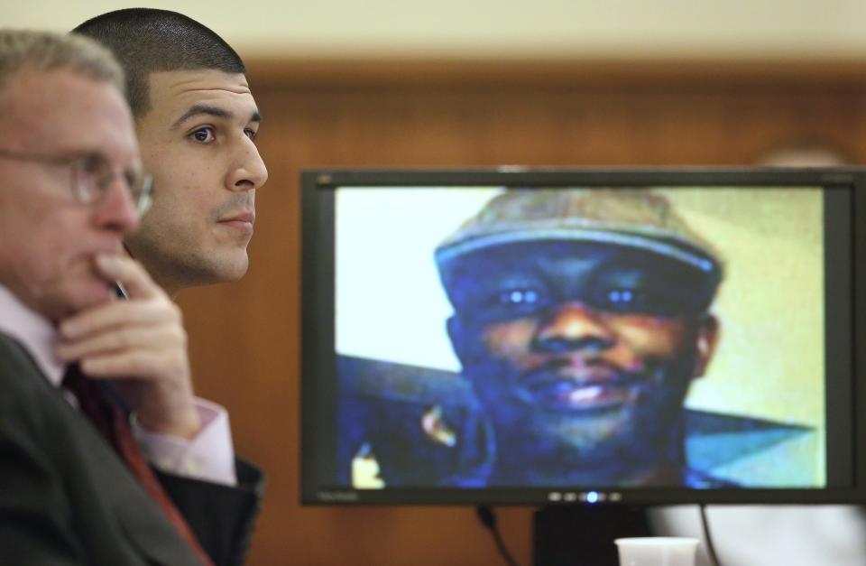 Former New England Patriots football player Aaron Hernandez listens during his trial as defense attorney Charles Rankin (L), looks on while an image of Odin Lloyd is displayed on a monitor in Fall River, Massachusetts, January 29, 2015. Hernandez is accused of murdering semi-professional football player Odin Lloyd. REUTERS/Steven Senne/Pool (UNITED STATES - Tags: CRIME LAW SPORT FOOTBALL)