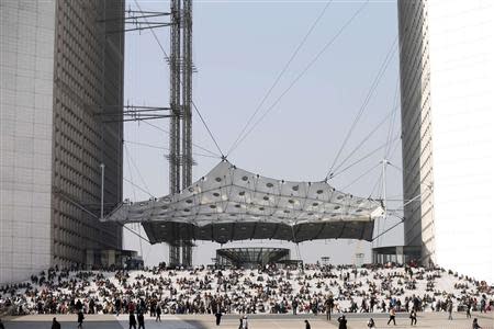 Businessmen enjoy the good weather at lunch time on the steps of the Arche de la Defense, in the financial and business district west of Paris, as warm and sunny weather continues in France, March 13, 2014. REUTERS/Charles Platiau