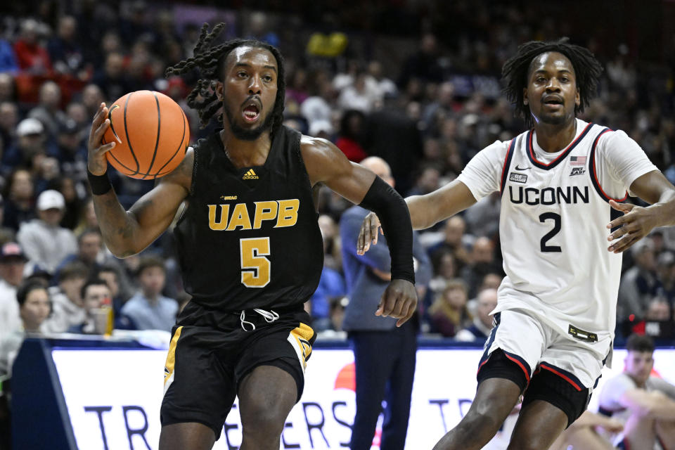 Arkansas-Pine Bluff guard Rashad Williams (5) drives to the basket as UConn guard Tristen Newton (2) defends in the first half of an NCAA college basketball game, Saturday, Dec. 9, 2023, in Storrs, Conn. (AP Photo/Jessica Hill)