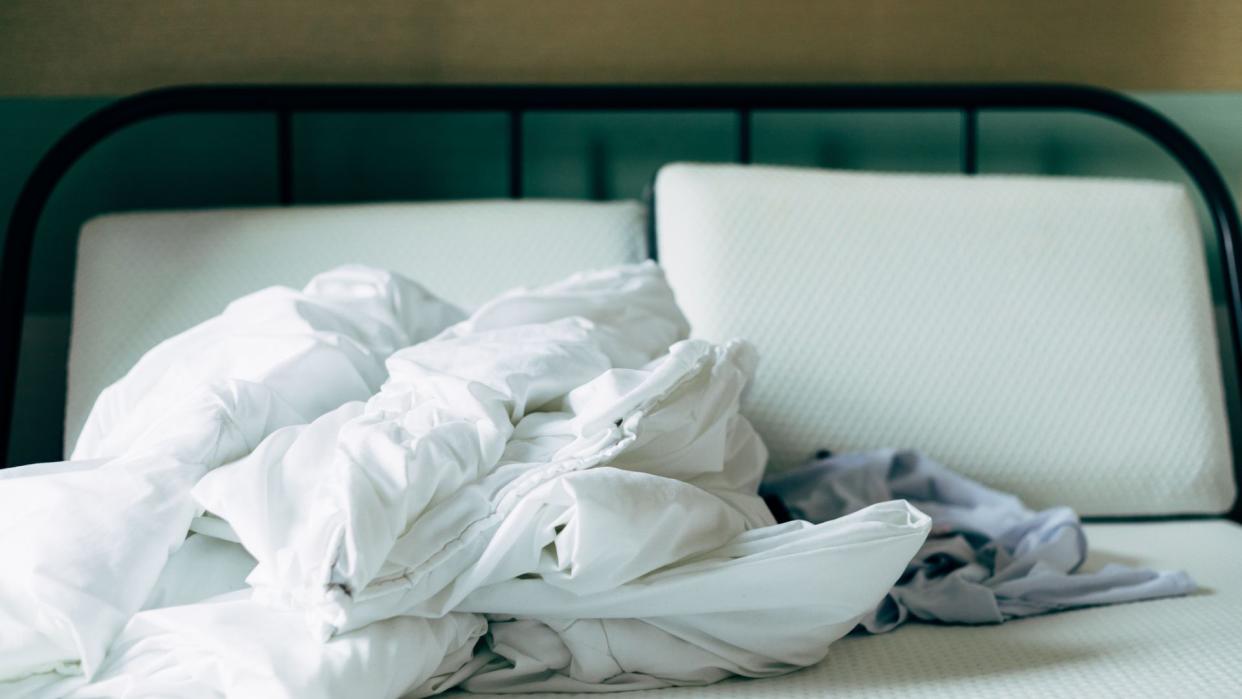  A mattress stripped of bedding on a black bed frame. 