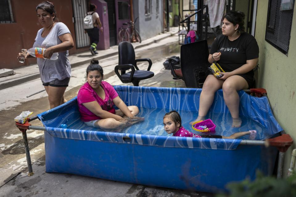 Miembros de la familia Sánchez se refrescan en una piscina de plástico fuera de su casa en el barrio Padre Carlos Múgica de Buenos Aires, Argentina, el miércoles 13 de diciembre de 2023. El gobierno argentino eliminó subsidios al transporte y energía y devaluó el peso a más de la mitad, de 400 a 800 pesos por dólar, como parte de las medidas de ajuste que el nuevo presidente, Javier Milei, defiende ante las urgencias económicas del país. (AP Foto/Rodrigo Abd)