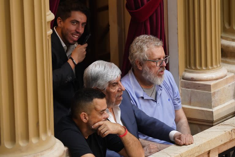 Hugo Moyano, en un palco inusual, escoltado por Daniel Menéndez (Barrios de Pie) y Esteban Castro (UTEP); atrás, sonriente, su hijo menor, Jerónimo