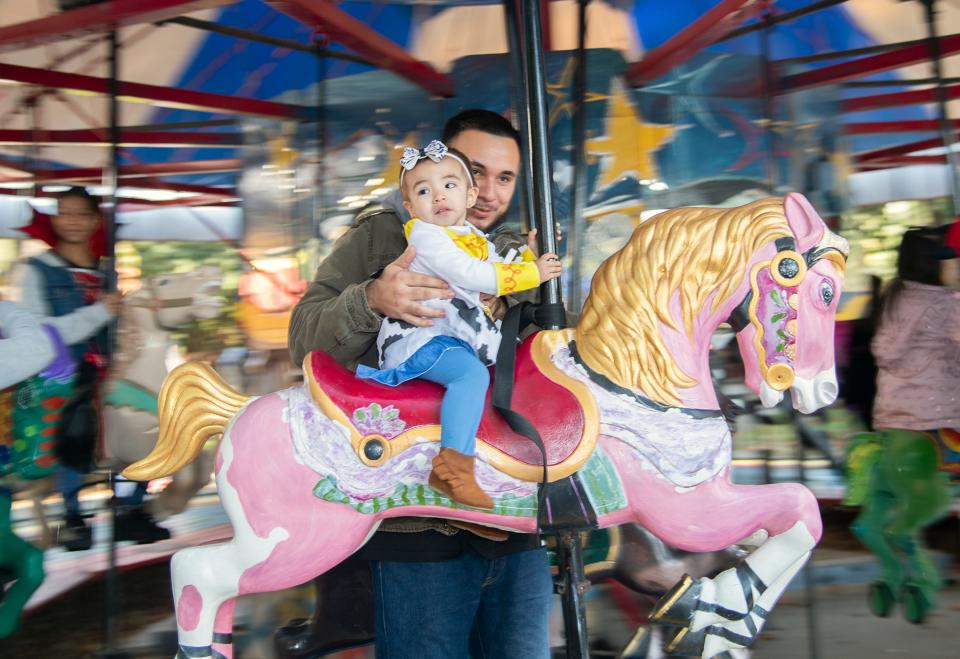 David Martinez and his 1-year-old daughter Katalina ride the carousel at Pixie Woods' Monster Mash Halloween bash in Stockton on Oct. 28, 2023. Children who wore a costume got in free during the season-ending event at the children's playland. CLIFFORD OTO/THE STOCKTON RECORD