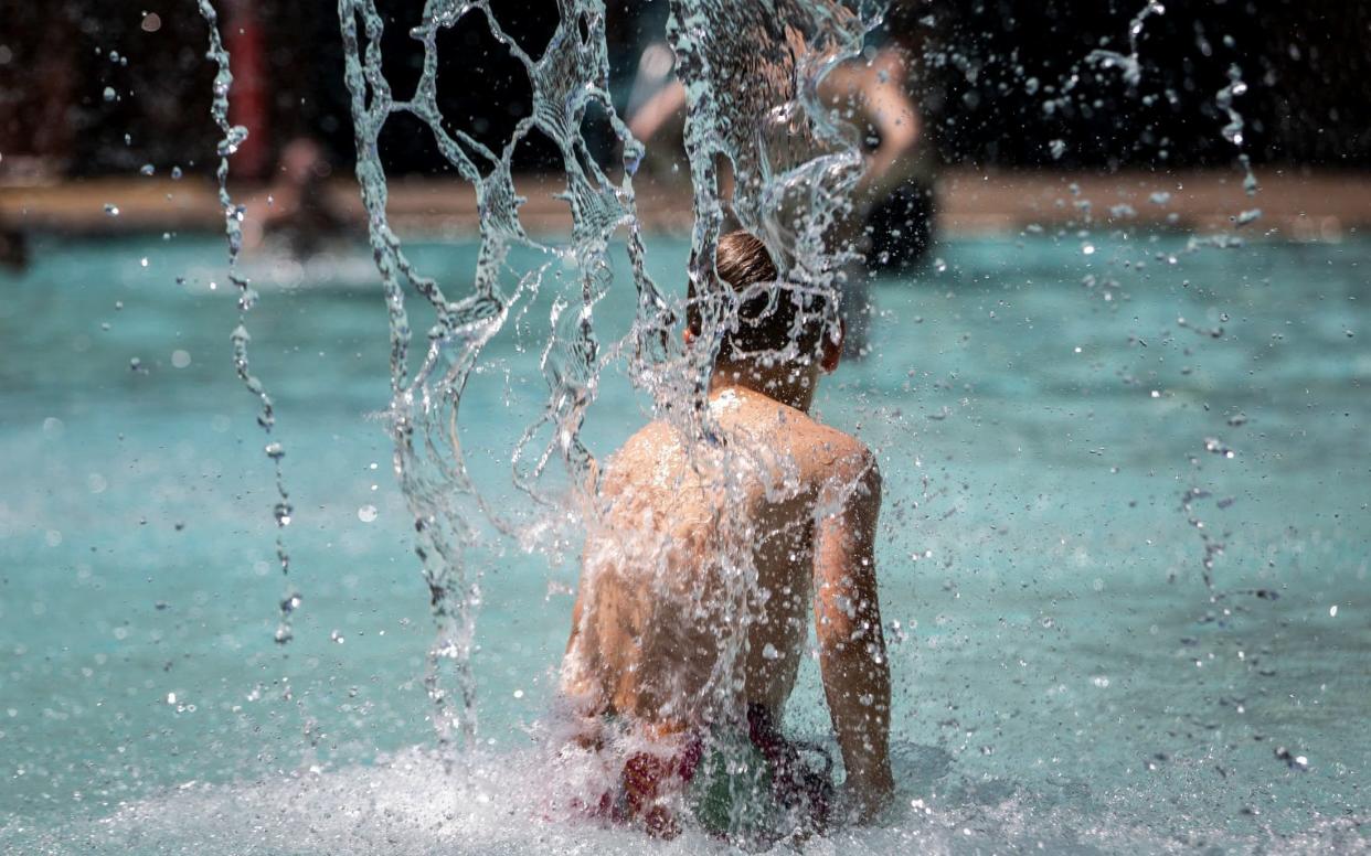 A young boy cools off in a swimming pool during hot weather in Portland - MARANIE STAAB /REUTERS