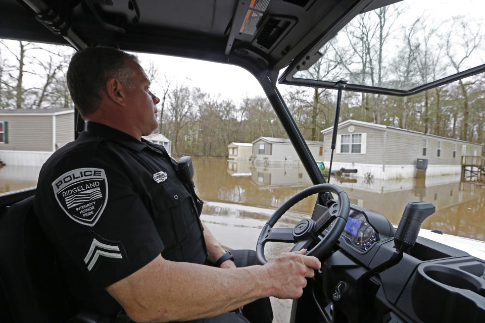 Ridgeland Police Cpl. Russell Dukette, drives through the standing floodwater from the Pearl River surrounds a number of mobile homes in the Harbor Pines community in Ridgeland, Miss., Tuesday, Feb. 18, 2020. While much of the water in the community receded overnight, there are areas that still have high water. (AP Photo/Rogelio V. Solis)