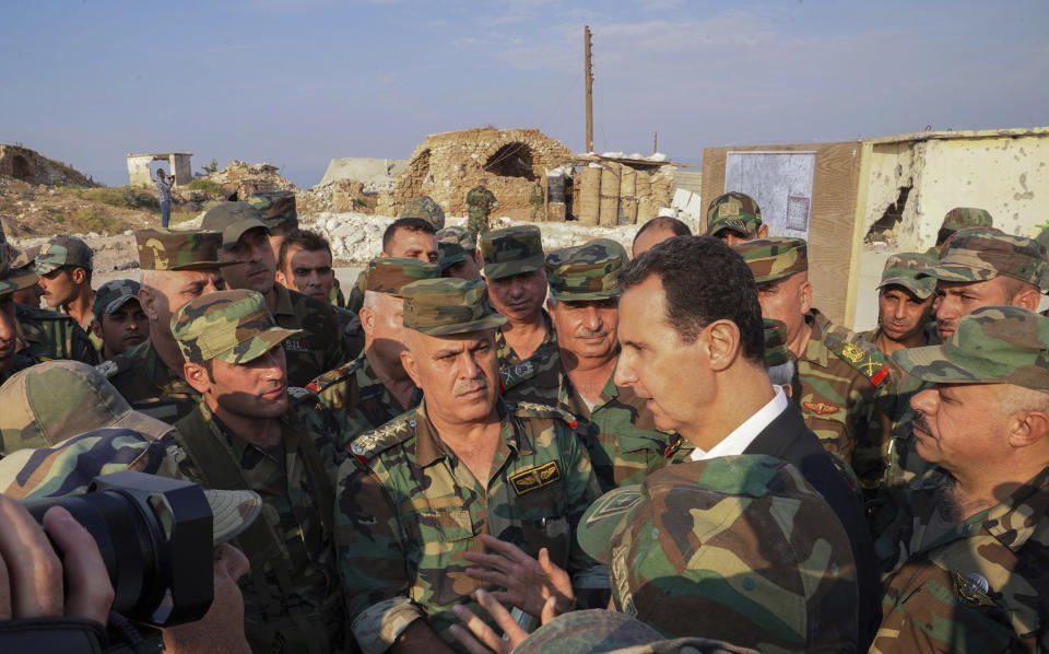 In this photo released on the official Facebook page of the Syrian Presidency, Syrian President Bashar Assad, center right, speaks with Syrian troops during his visit to the strategic town of Habeet, in the northwestern province of Idlib, Syria, Tuesday, Oct. 22, 2019. On Tuesday, Assad called the Turkish President Recep Tayyip Erdogan a "thief" during his first visit to territory captured from Turkey-backed rebels in the northwestern province of Idlib. (Facebook page of the Syrian Presidency via AP)