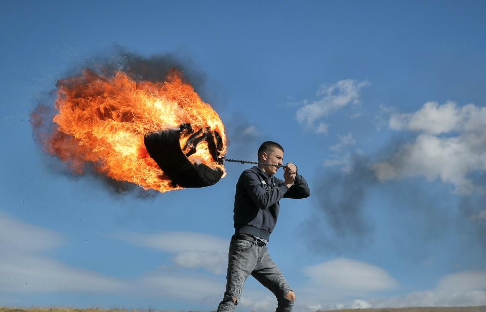 In this photo taken on Sunday, March 10, 2019, a young man spins a burning tire on a metal chain during a ritual marking the upcoming Clean Monday, the beginning of the Great Lent, 40 days ahead of Orthodox Easter, on the hills surrounding the village of Poplaca, in central Romania's Transylvania region. Romanian villagers burn piles of used tires then spin them in the Transylvanian hills in a ritual they believe will ward off evil spirits as they begin a period of 40 days of abstention, when Orthodox Christians cut out meat, fish, eggs, and dairy. (AP Photo/Vadim Ghirda)