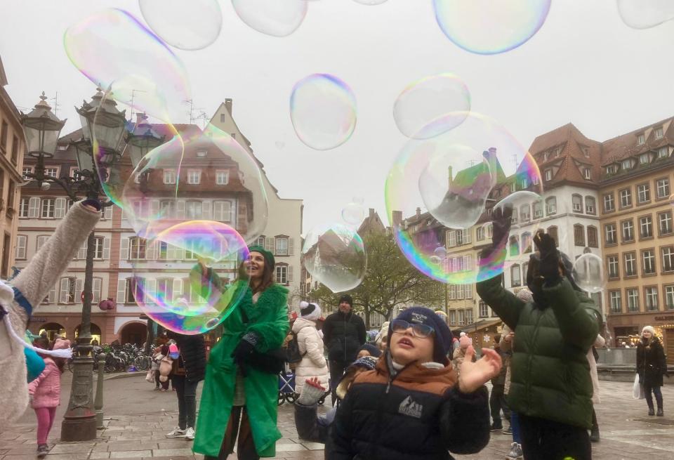 School children chase a parade of bubbles giving color to a gray day across the Place Gutenberg in Strasbourg, France, which honors the inventor of the printing press.