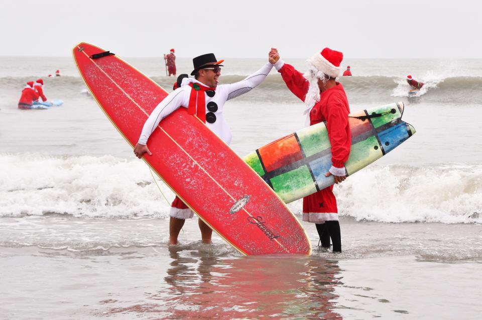 George Trosset Jr. and George Trosset, the two that started it all in Cocoa Beach, high five each other during another Surfing with Santa event.