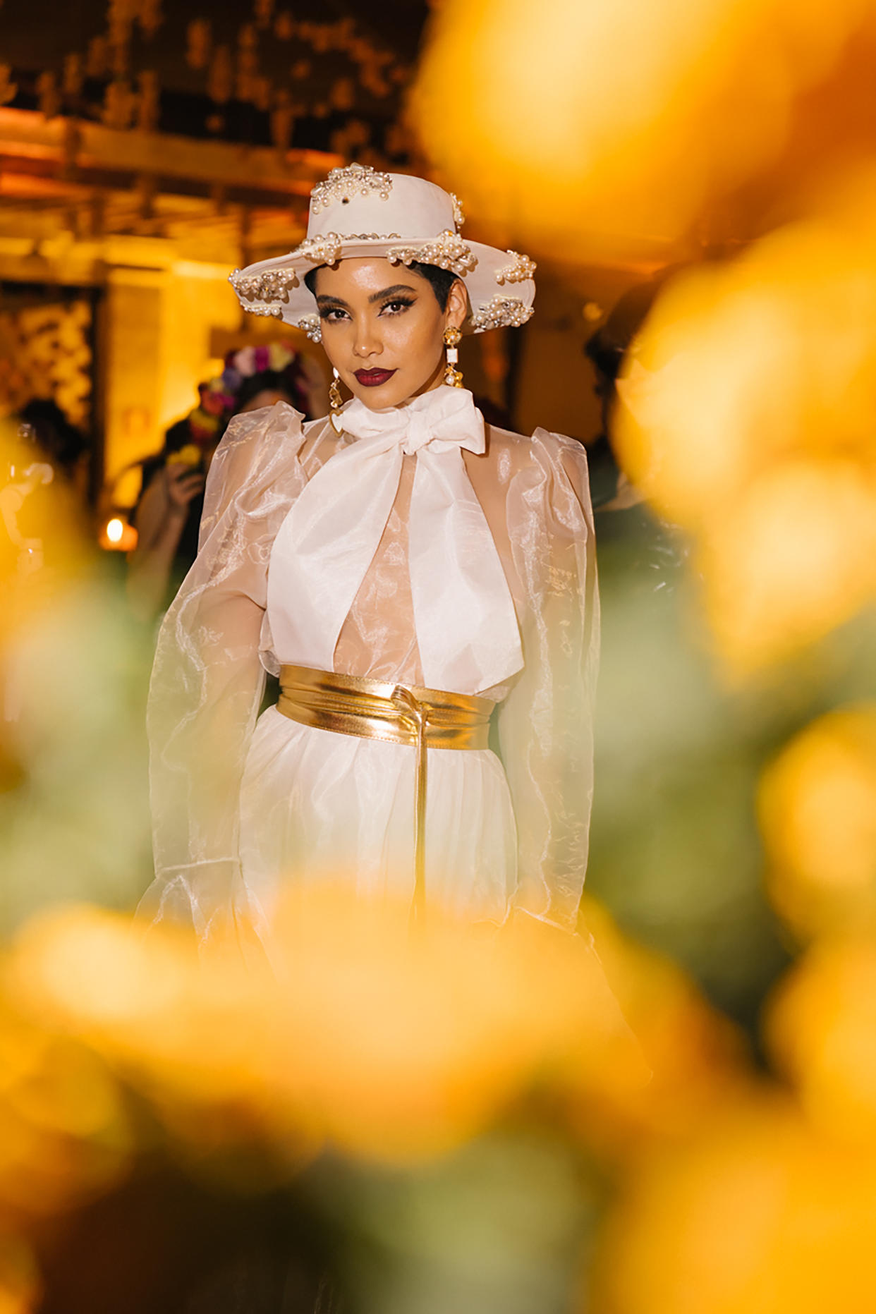La modelo Andrea Bazarte agregó a su atuendo blanco accesorios como un cinturón dorado en la tercera gala con que Vogue México celebra el Día de Muertos, en el Museo Numismático Nacional en Ciudad de México el 27 de octubre de 2022. (Alicia Vera/The New York Times)