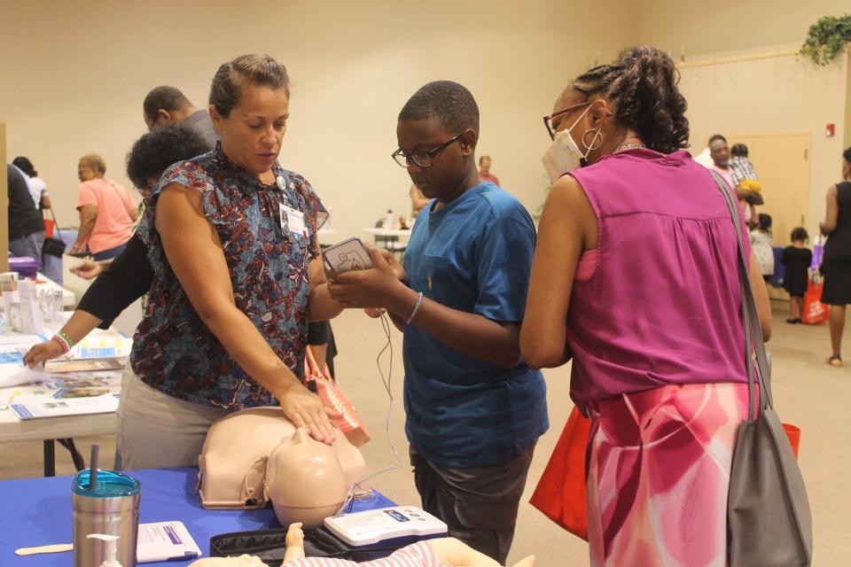 Mount Moriah Baptist Church held its 19th annual Nurses Guild Program that featured a health fair after an abbreviated Sunday morning worship service. During the health fair, Elizabeth Warren, left, UF Health's chest pain coordinator, teaches parishioners Ryan Adams, center, and Synester Rollins, right, about chest compressions.
(Credit: Photo by Voleer Thomas/For The Guardian)