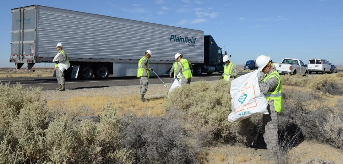 Laboratory airmen from Edwards Air Force Base pick up trash on Highway 58 as part of Caltrans' Adopt-A-Highway program, which will now pay individuals and groups to clean up.