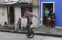 Residents watch a performance by troupe members of "Circo Encuentro" as they wait for soup the troupe prepared with donated food items, in Bogota, Colombia, Saturday, July 4, 2020. The troupe prepares a "sopita de murcielago" or bat soup community kitchen style in a selected neighborhood for residents who have been economically affected by the COVID-19 related shutdowns. (AP Photo/Fernando Vergara)