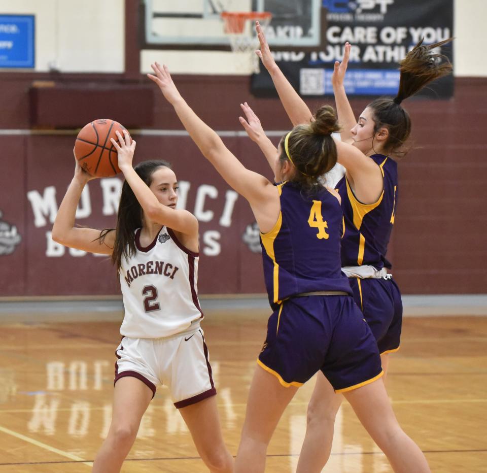 Evelyn Joughin of Morenci looks to pass off as she is double-teamed by Avery Collins (4) and a Bllissfield teammate.