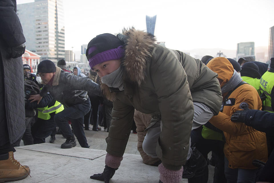 Protesters scramble up the steps of the State Palace on Sukhbaatar Square in Ulaanbaatar in Mongolia on Monday, Dec. 5, 2022. Protesters angered by allegations of corruption linked to Mongolia's coal trade with China have stormed the State Palace in the capital, demanding dismissals of officials involved in the scandal. (AP Photo/Alexander Nikolskiy)