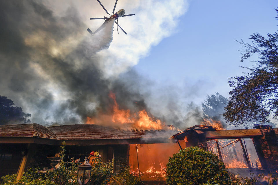 <p>A helicopter dumps water on a home as firefighters battle a wildfire in Anaheim Hills in Anaheim, Calif., Monday, Oct. 9, 2017. Wildfires whipped by powerful winds swept through Northern California sending residents on a headlong flight to safety through smoke and flames as homes burned. (Photo: Jeff Gritchen/The Orange County Register via AP) </p>