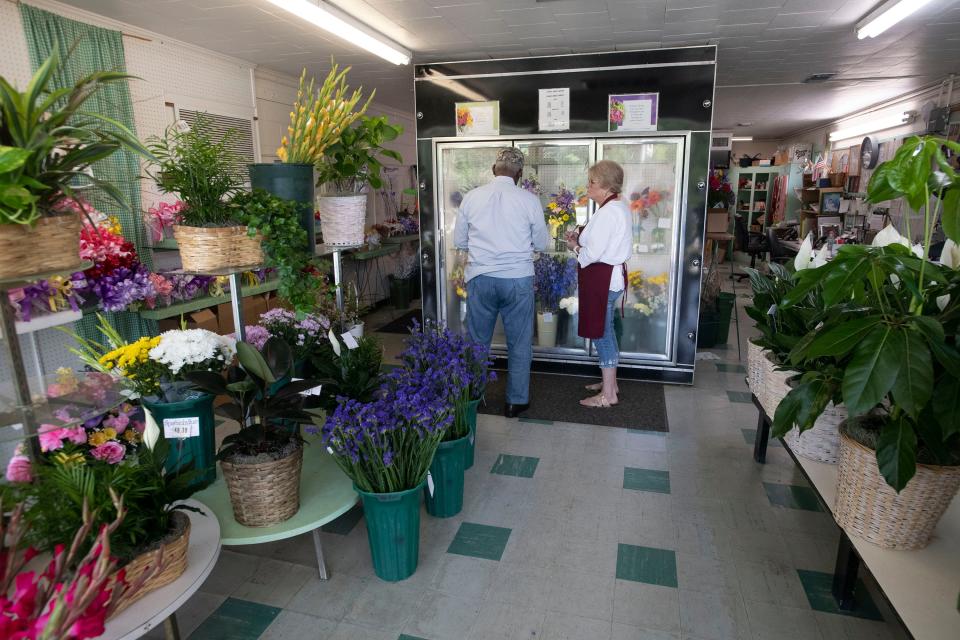 Grandview Florist customer Henry Arnold gets help from Kathy Elliott while shopping for flowers Wednesday.