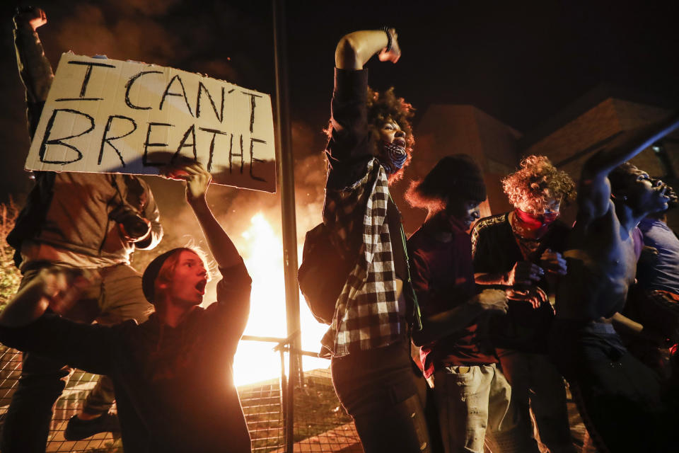 Protestors demonstrate outside of a burning Minneapolis 3rd Police Precinct, Thursday, May 28, 2020, in Minneapolis. Protests over the death of George Floyd, a black man who died in police custody Monday, broke out in Minneapolis for a third straight night. (AP Photo/John Minchillo)