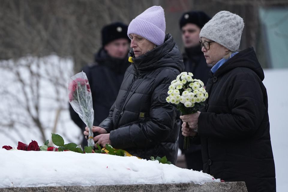 Women lay flowers to pay tribute to Alexei Navalny at the monument, a large boulder from the Solovetsky islands, where the first camp of the Gulag political prison system was established, near the historical Federal Security Service (FSB, Soviet KGB successor) building in Moscow, Russia, on Saturday, Feb. 24, 2024. Navalny, 47, Russia’s most well-known opposition politician, unexpectedly died on Feb. 16 in the penal colony, prompting hundreds of Russians across the country to stream to impromptu memorials with flowers and candles. (AP Photo/Alexander Zemlianichenko)