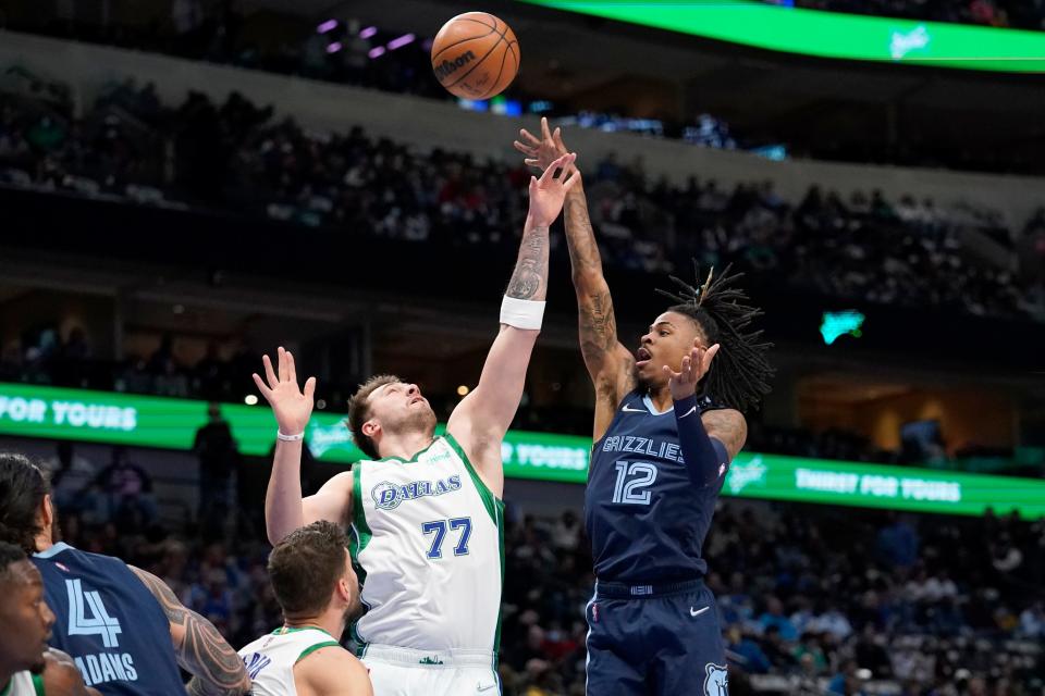 Dallas Mavericks guard Luka Doncic (77) defends as Memphis Grizzlies guard Ja Morant (12) shoots in the first half of an NBA basketball game in Dallas, Sunday, Jan. 23, 2022. (AP Photo/Tony Gutierrez)