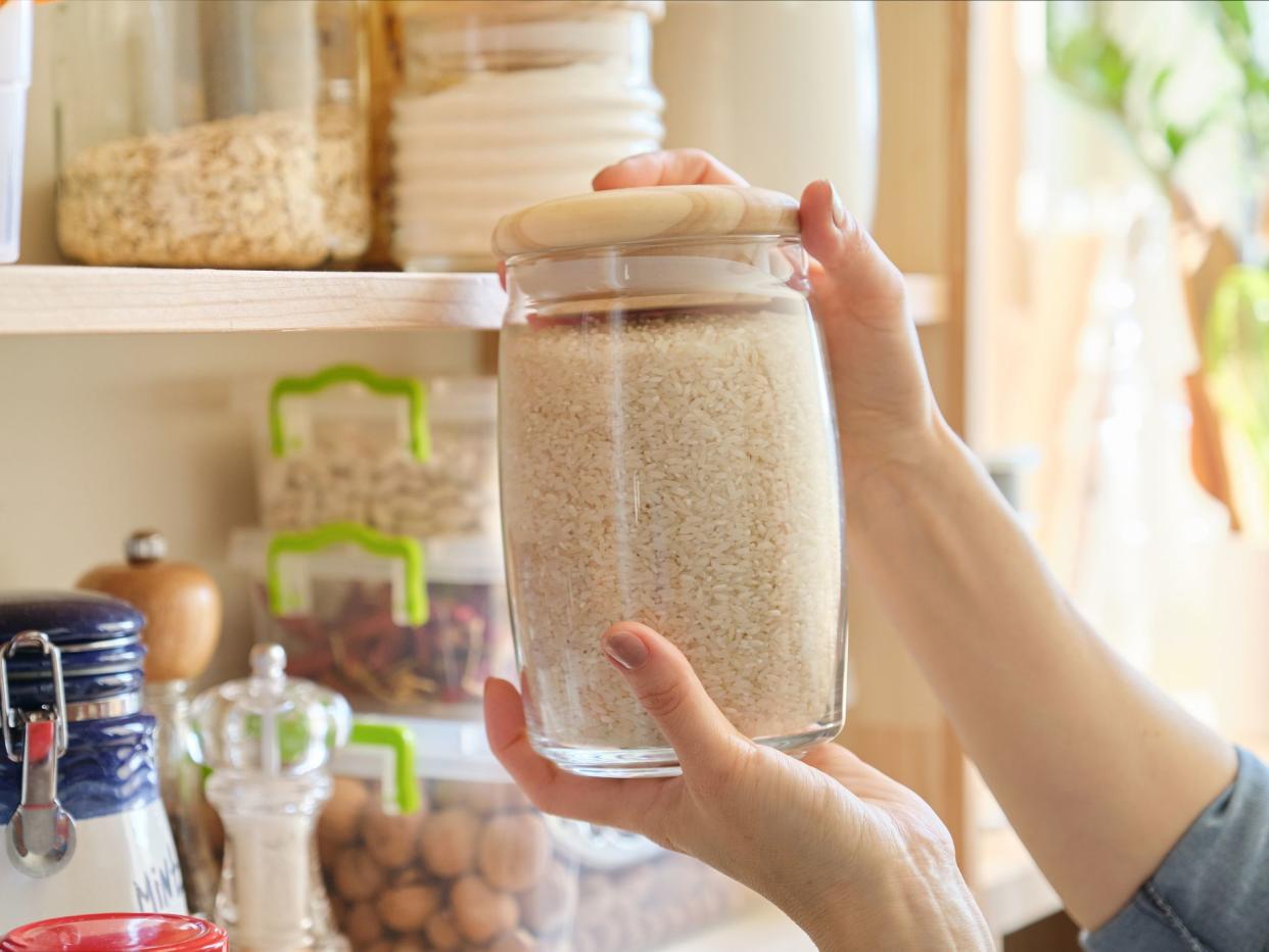 Food products in the kitchen storing ingredients in pantry. Woman taking jar of rice