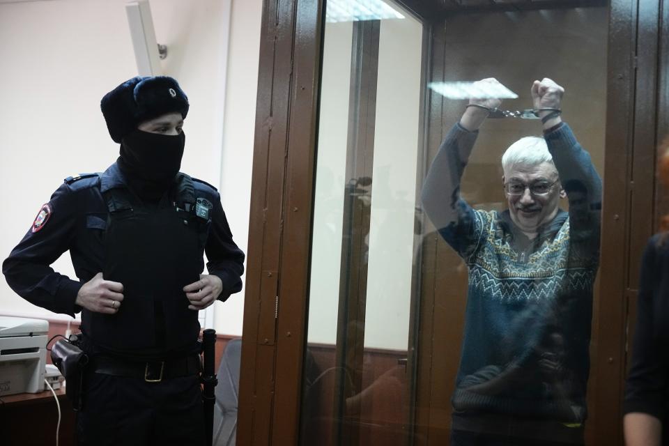 FILE - Oleg Orlov, co-chair of the Nobel Peace Prize-winning organization Memorial, gestures from a glass cage while on trial on charges of repeated discrediting the Russian military, in Moscow on Feb. 27, 2024. Orlov was sentenced to 2 1/2 years in prison. (AP Photo, File)