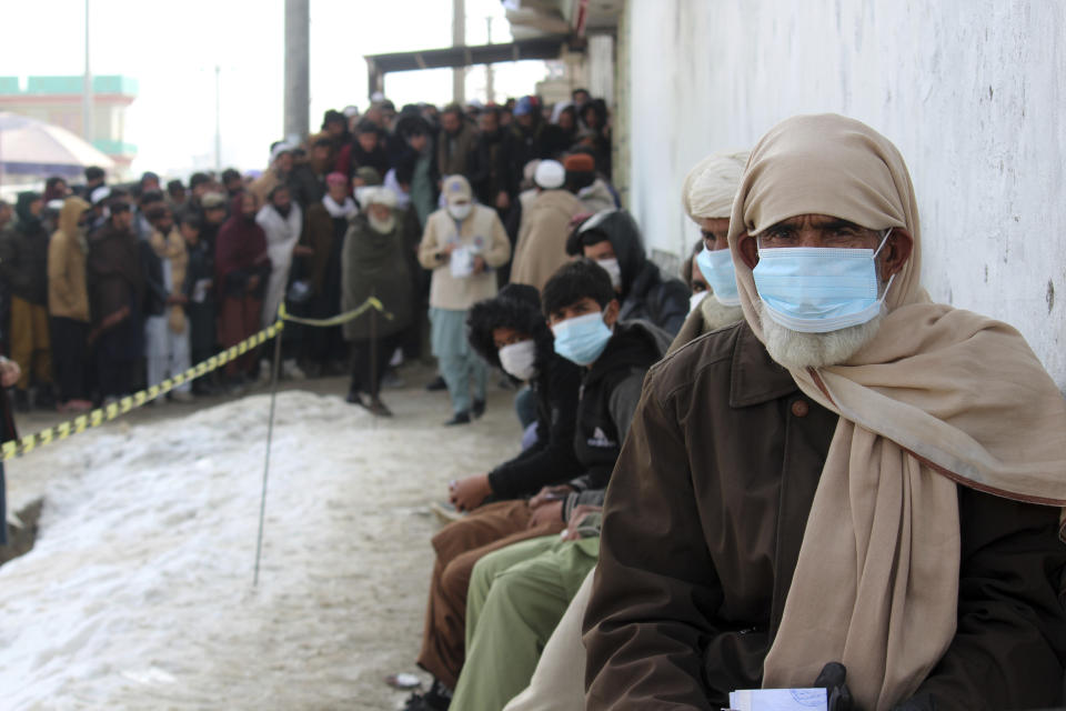 Afghans wait to receive food rations organized by the World Food Program (WFP) in Pul-e-Alam, the capital of Logar province, eastern of Afghanistan, Tuesday, Jan. 18, 2022. The Taliban's sweep to power in Afghanistan in August drove billions of dollars in international assistance out of the country and sent an already dirt-poor poor nation, ravaged by war, drought and floods, spiralling toward a humanitarian catastrophe. (AP Photo/Zubair Abassi)