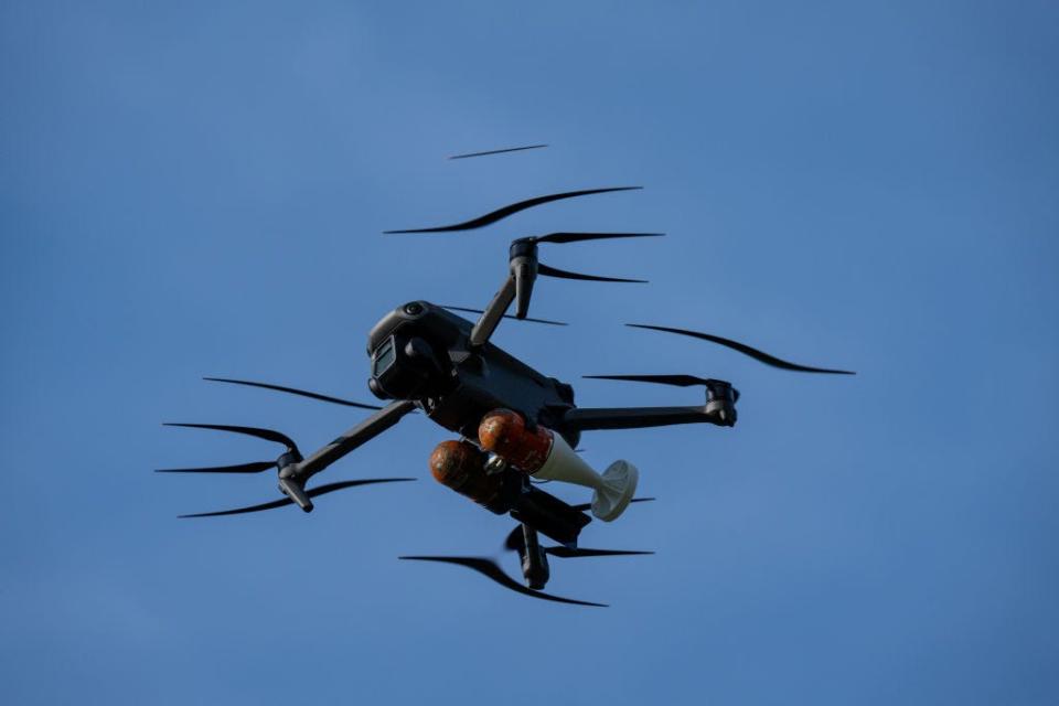 A drone in the sky carrying dummy grenades.