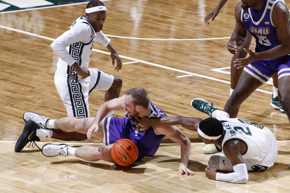 James Madison's Noah Freidel, center, and Michigan State's Tre Holloman, left, and Tyson Walker, right, scramble for a loose ball during the first half of an NCAA college basketball game, Monday, Nov. 6, 2023, in East Lansing, Mich. (AP Photo/Al Goldis)