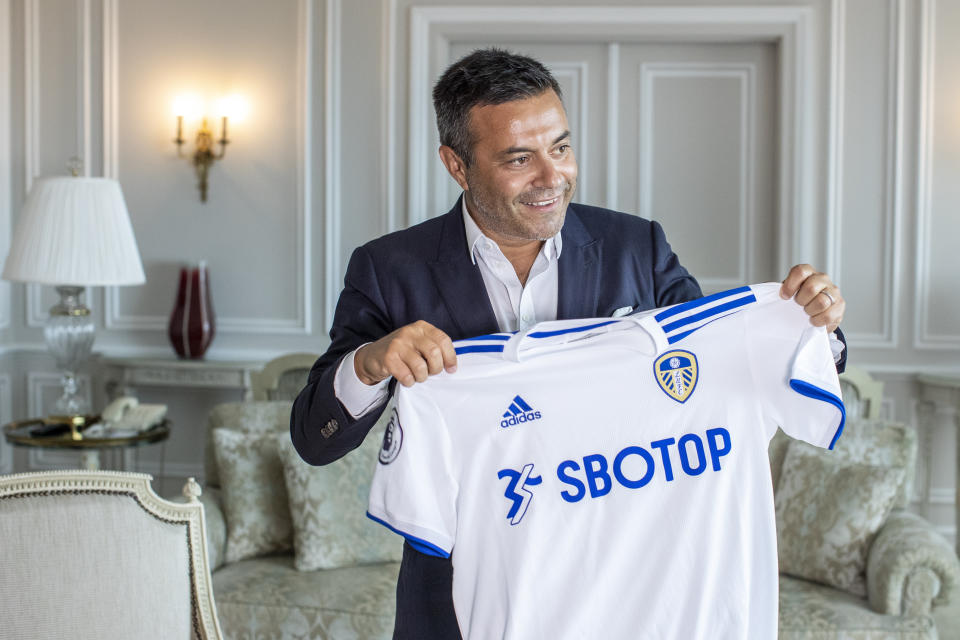 In this photo taken on Wednesday, Aug. 19, 2020, Leeds owner Andrea Radrizzani holds a Leeds shirt, during an interview with the Associated Press in Lisbon, Portugal. Leeds is counting on Marcelo Bielsa leading the team in the Premier League while planning for a future without the enigmatic manager. In his second season in charge, the Argentine ended the team’s 16-year exile from the world’s richest league by gaining promotion as Championship winners before his contract expired last month. (AP Photo/Manu Fernandez)
