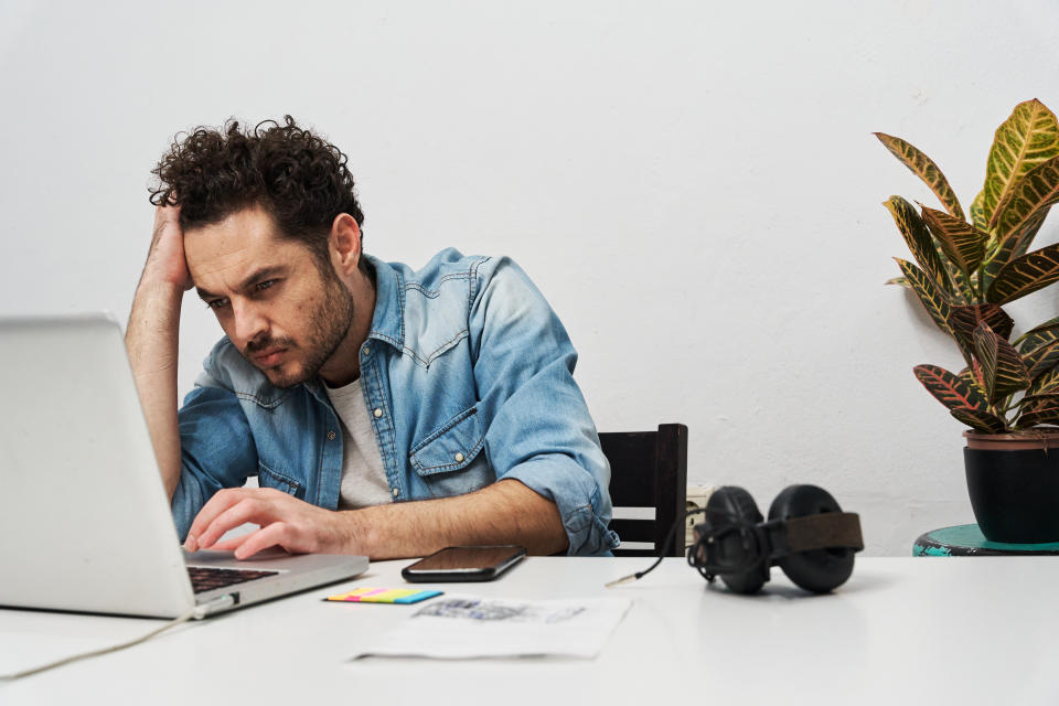 Tired and stressed businessman working with a laptop at home. Home office and freelance concept.