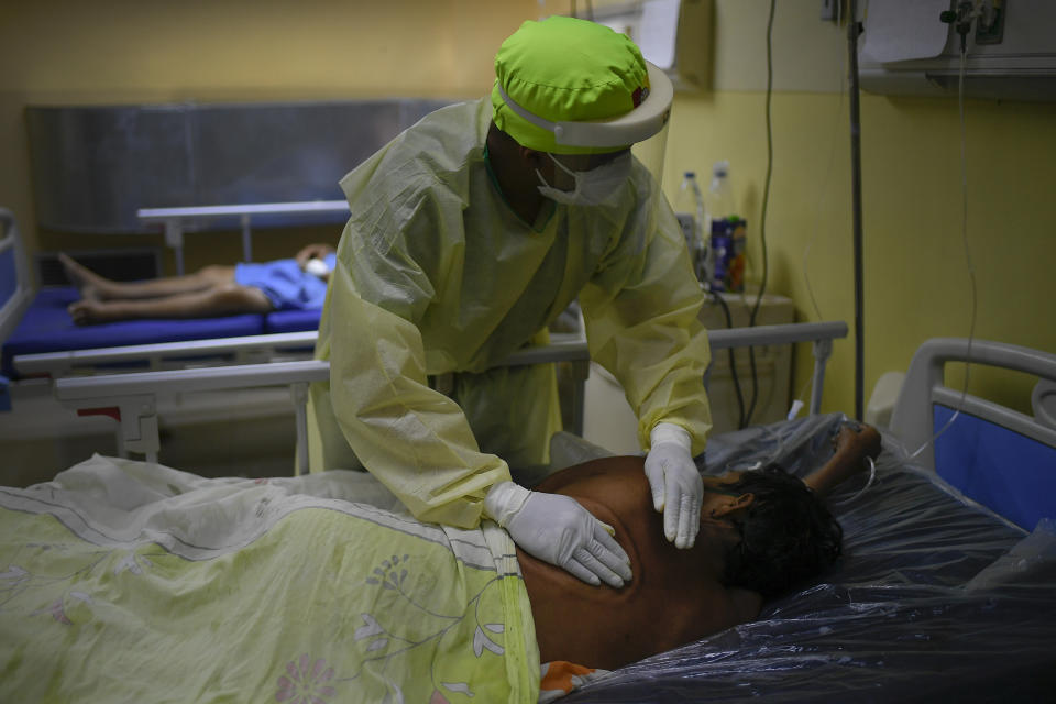 A health worker gives pats on the back of a COVID-19 patient at the intensive care unit of the Ana Francisca Perez de Leon II public Hospital in Caracas, Venezuela, Saturday, March 27, 2021. (AP Photo/Matias Delacroix)