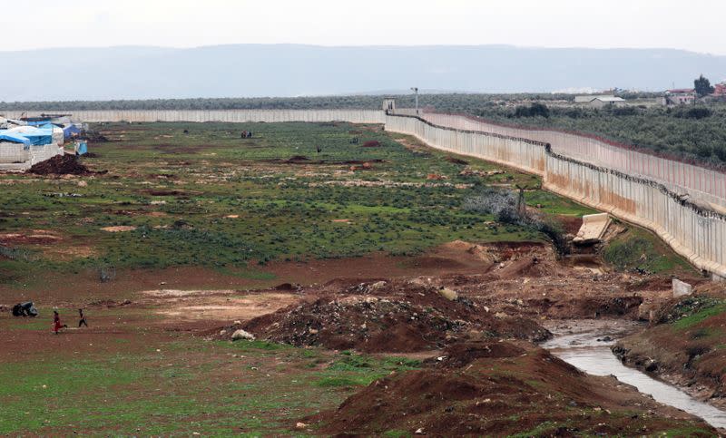 Internally displaced Syrians run near the wall in Atmah IDP camp, located near the border with Turkey