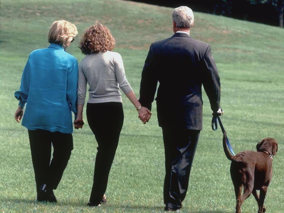 President Bill Clinton, first lady Hillary Clinton, and their daughter Chelsea walk with the family dog, Buddy, August 18, 1998, from the White House toward a helicopter as they depart for a vacation to Martha's Vineyard, Massachusetts.