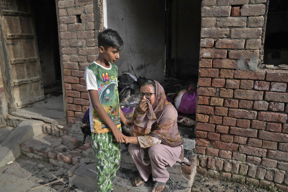 Un niño cristiano consuela a una mujer que llora tras ver su casa destrozada por una turba en Jaranwala, en el distrito de Faisalabad, Pakistán, el jueves 17 de agosto de 2023. La policía detuvo a más de 100 musulmanes en redadas durante la noche en el este de Pakistán, donde una turba de musulmanes enojados por la supuesta profanación de un Corán por parte de un hombre cristiano atacó iglesias y viviendas de la minoría cristiana. (AP Foto/K.M. Chaudary)