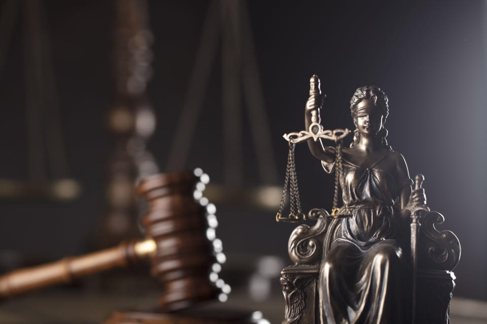 Themis, gavel and scale on wooden desk.