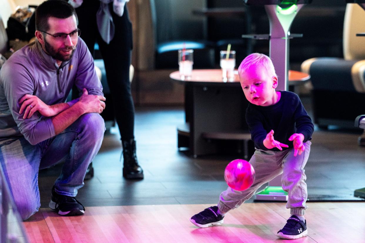Tim Mack, left, watches his son Brooks, 3, throw a bowling ball at Putts & Pins, 6920 EP True Parkway in West Des Moines.