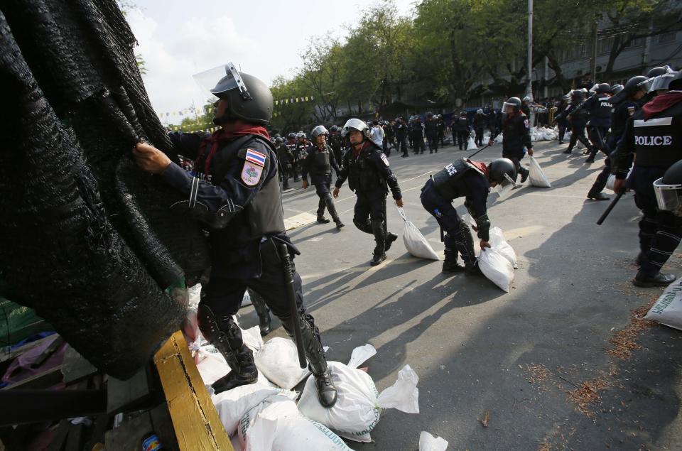 Riot police remove sandbags, meshing and other obstacles as they retake a stretch of a road from anti-government protesters in Bangkok, Thailand, Friday, Feb. 14, 2014. Riot police cleared the protesters from a major boulevard in the Thai capital in a small victory for authorities Friday as they try to reclaim areas that have been closed during a three-month push to unseat Prime Minister Yingluck Shinawatra. (AP Photo/Wally Santana)