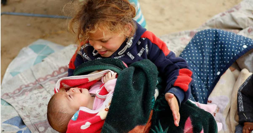 一名巴勒斯坦男同抱著哭泣的嬰兒。（圖／達志／路透社）