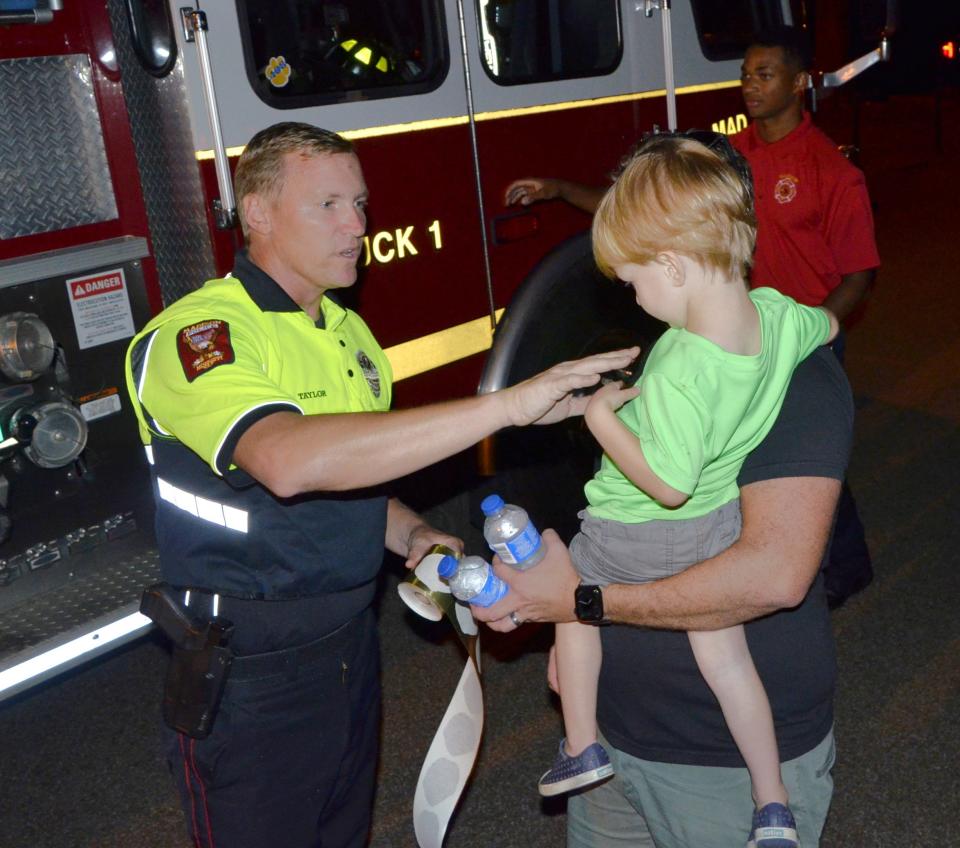 Lt. Micah Taylor with the Madison Police Department places a sticker badge on the shirt of Nate Grcich, 2, of Madison during the Night Out festivities held at the Summertree Clubhouse in Madison on Tuesday, Oct. 3.