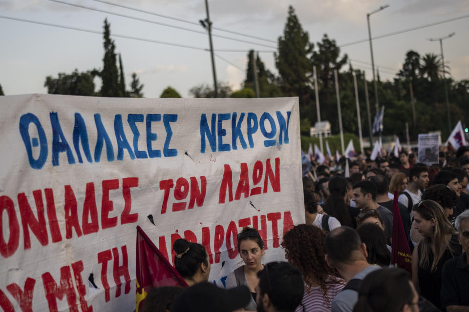 Protesters hold a banner which reads in Greek with blue letters "Seas of Dead", during a demonstration in front of the parliament building, following a deadly migrant shipwreck off Greece, in Athens, on Thursday, June 15, 2023. Greece declared three days of mourning after a fishing boat crammed to the gunwales with migrants trying to reach Europe capsized and sank Wednesday off the coast of Greece, authorities said, killing and missing multiple people in one of the worst disasters of its kind this year. (AP Photo/Petros Giannakouris)