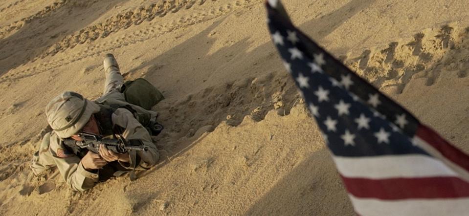 This Jan. 25, 2003 file photo shows an US soldier lying with his rifle in front of an American flag that hangs from a Humvee during live fire exercises in the Kuwaiti desert south of Iraq. (Laura Rauch/AP)