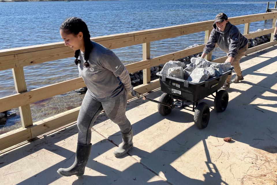 AmeriCorps members Maria Sanchez and Sarah Smith pull a wagon of limestone rock as they help build a breakwater at Liza Jackson Park on Thursday. When completed, the Choctawhatchee Basin Alliance project will extend along most of the park's waterfront.