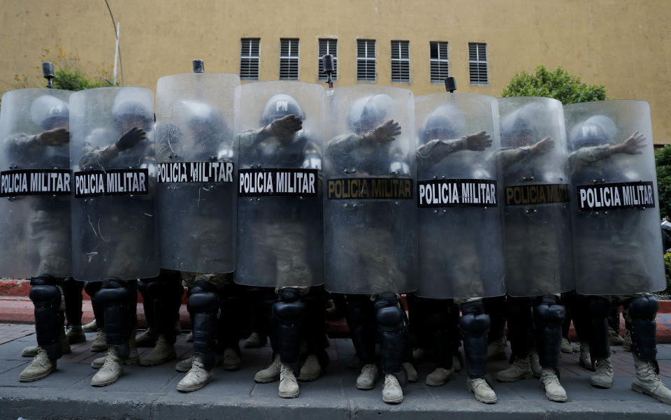 Military Police take cover behind their shields during a march of supporters of former President Evo Morales in La Paz, Bolivia, Thursday, Nov. 14, 2019. Morales resigned and flew to Mexico under military pressure following massive nationwide protests over alleged fraud in an election last month in which he claimed to have won a fourth term in office. (AP Photo/Natacha Pisarenko)