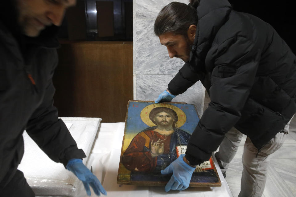 Museum workers unpack an icon returned from Albania upon the arrival at the National museum in Skopje, North Macedonia, late Friday, Dec. 15, 2023. Albania on Friday returned 20 icons to neighboring North Macedonia that were stolen a decade ago. (AP Photo/Boris Grdanoski)