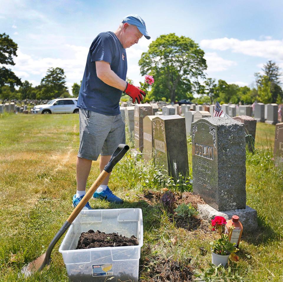 Bill Yourell, 70, of Duxbury, plants flowers at his grandparents' grave in Mount Wollaston Cemetery in Quincy on Monday, May 23, 2022.