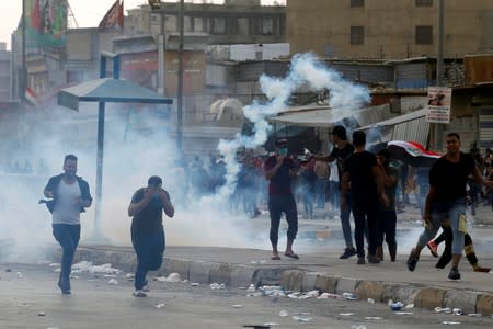 Demonstrators disperse as Iraqi security forces use tear gas during a protest over unemployment, corruption and poor public services, in Baghdad