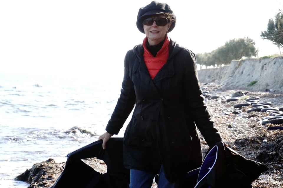 Susan stands on the beach in Lesbos holding life vests