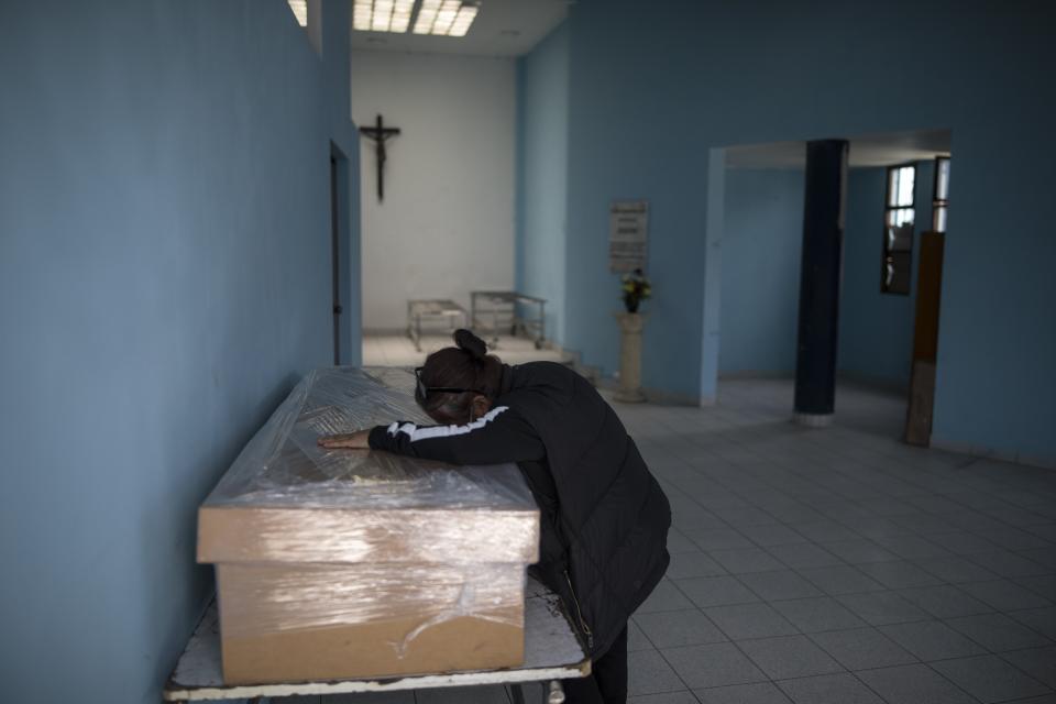 FILE - In this Sept. 23, 2020 file photo, Elizabeth Alvarado cries over the cardboard coffin containing the remains of her husband Victor Arguelles, who died from complications related to the new coronavirus, at El Angel cemetery in Lima, Peru. Today the South American nation has the highest per capita COVID-19 mortality rate of any country across the globe, according to John Hopkins University – and physicians there believe the country’s faulty testing approach is one reason why. (AP Photo/Rodrigo Abd, File)